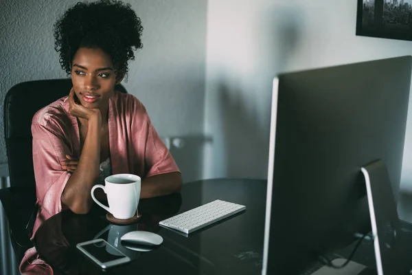 black woman at home working with computer and coffee in the morning