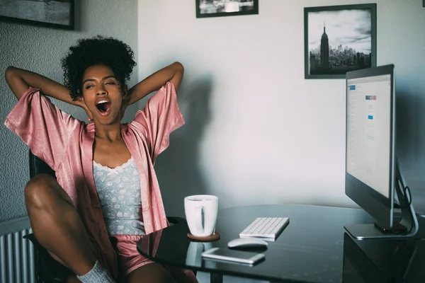 black woman at home stretching with computer and coffee in the morning