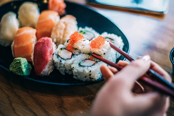 Crop woman eating sushi on background