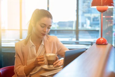 Dizüstü bilgisayar, akıllı telefon ve kahve bir restoranda genç güzel kadın