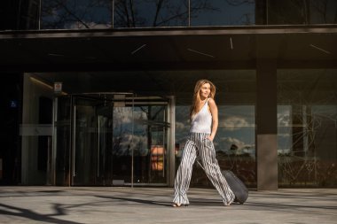 Bavullu genç bir kadın sokakta yürüyor.