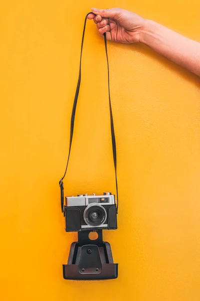 Hand holding a Vintage camera isolated at orange wall