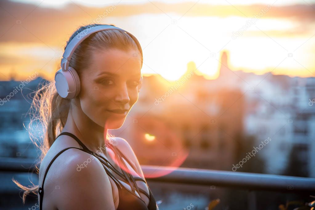 sportswoman outdoors in the gym resting enjoying the city views listening music