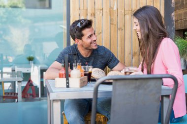 Hamburger yeme restoranın terasında mutlu genç çift oturma grubu