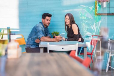 Mutlu genç çift oturma bir restoranda bir akıllı telefon ile