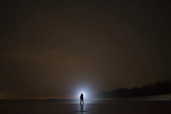 Kış manzara gölde buz üzerinde duran insan. El feneri ile gece parlayan. Scandinavia Europe İsveç. 
