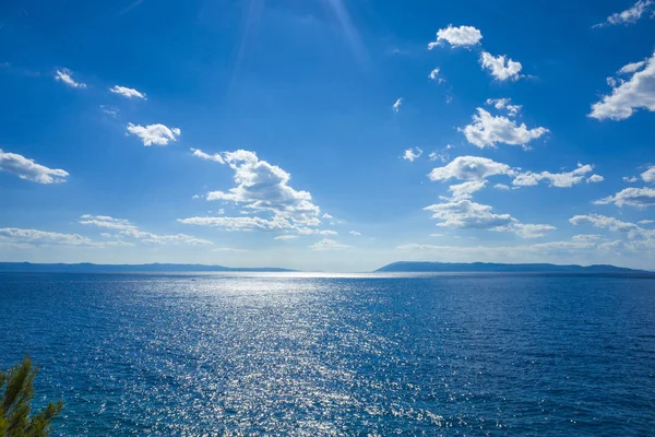 Hot sunny summer day with blue sky and ocean. Mountains at horizon and white clouds. Adriatic Sea in Croatia Europe. Beautiful and relaxing photo with nice colors.