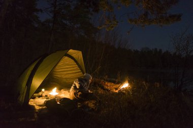 Kamp ateşinin yanındaki çadırda oturan bir kadın. etkin boş zaman 