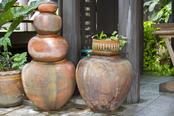 Viejos tarros de barro naranja apilados junto a un poste de madera . — Foto de Stock