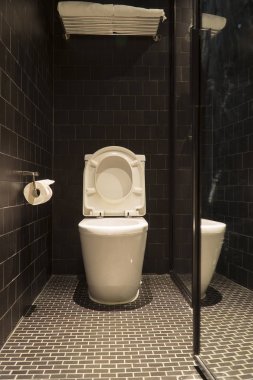 Siyah banyo beyaz tuvalet ve beyaz havlu var