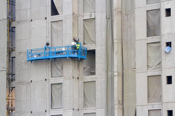 労働者が付いている建物の横にある青い建設バスケット — ストック写真