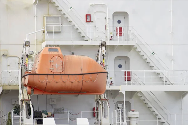 An emergency orange boat attaches to a large white ship.