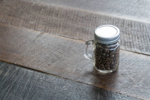 Kaffebönor i glasflaskor med gammalt trägolv — Stockfoto