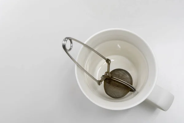 Сетчатый фильтр для чая весенняя сетка мяч корпус старого в белой чашке — стоковое фото