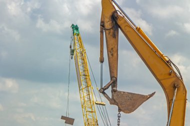Sarı kepçe nehir kenarında ve yol kenarında çalışıyor.