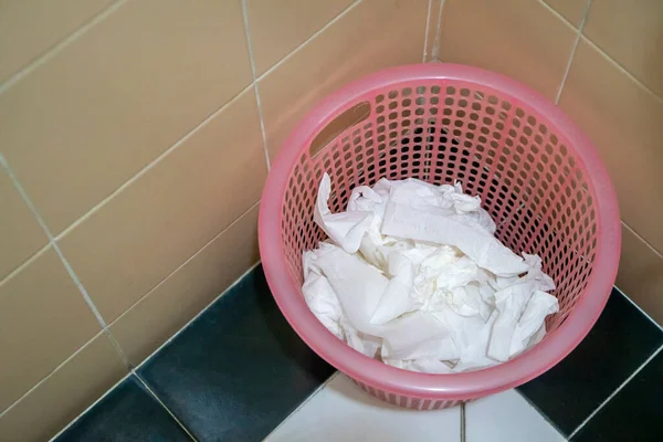 Tissue in the trash pink basket in bathroom