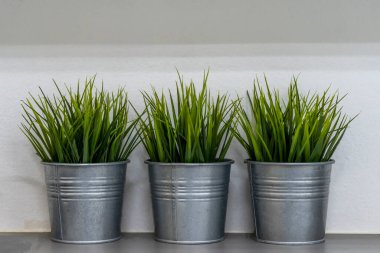 Yapay ağaçlı çinko saksısı evi süslüyor.