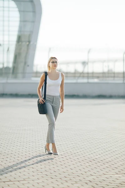 Business woman goes on the street at sunset