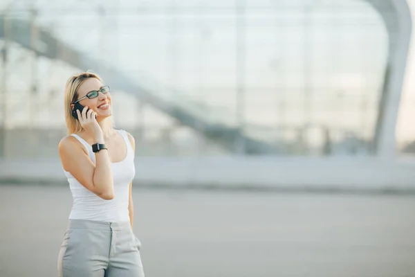 Attraktive Geschäftsfrau mit Sonnenbrille in grauer Hose telefoniert — Stockfoto