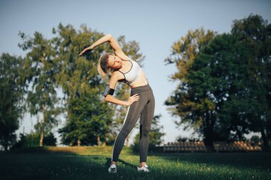 Kadın parkta yoga egzersizi yapıyor.