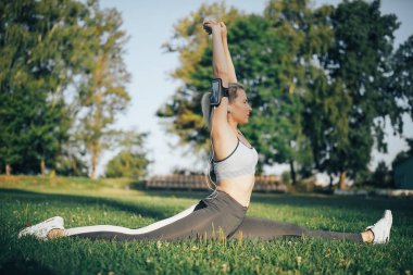 Kadın parkta yoga egzersizi yapıyor.