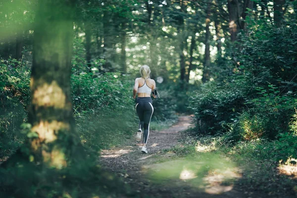 Привлекательная блондинка, фитнес-женщина бегает в утреннем лесу — стоковое фото