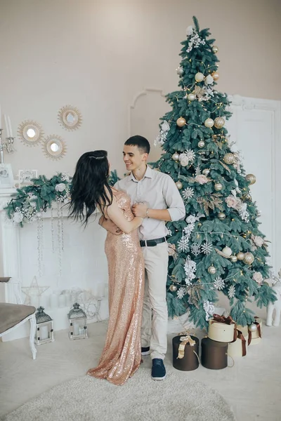 Mladý pár s úsměvem zatímco oslavuje doma u vánočního stromu — Stock fotografie