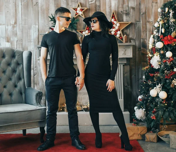 Dva mladí lidé stojící před krbem u vánočního stromu — Stock fotografie