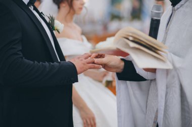 Rahip, ortodoks düğün töreninde damatların parmağına yüzük takıyor.