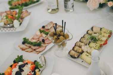 Yemek masasını soğuk abur cuburlarla donatmış. Masada çeşitli lezzetli atıştırmalıklar var..