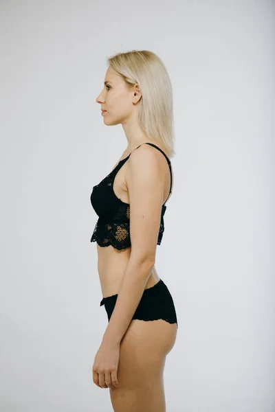 Sensuele vrouw draagt zwarte lingerie poseren, geïsoleerd op witte achtergrond — Stockfoto
