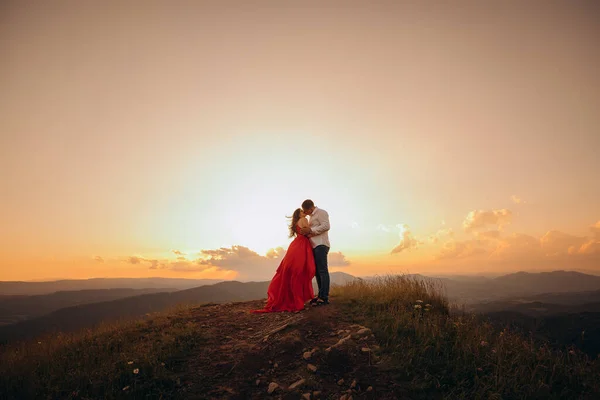 Приваблива молода пара цілується, займаючись прелюдією, торкаючись один одного. Щаслива пара стоїть в обіймах і цілує один одного на красивому заході сонця . — стокове фото