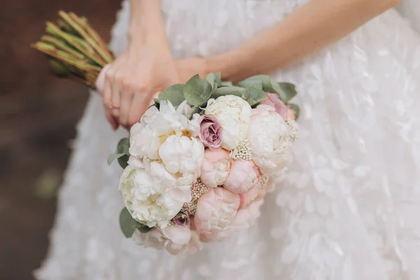 Noiva segurando seu lindo buquê. Fechar-se de uma noiva de vestido branco segurando seu buquê de casamento . — Fotografia de Stock