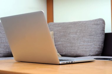 Oturma odasındaki ofis ortamındaki bir masada dizüstü bilgisayarda görüntüle.