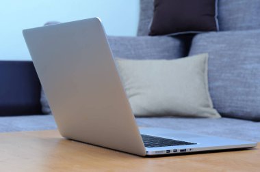 Oturma odasındaki ofis ortamındaki bir masada dizüstü bilgisayarda görüntüle.