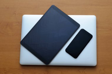 Oturma odasındaki ofis ortamında akıllı telefon ve tabletle birlikte kapalı bir bilgisayarda görüntüle.