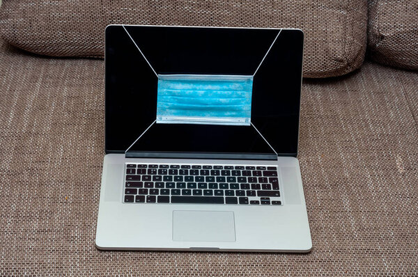 View on a medical mask protection against flu and other diseases like coronavirus on a laptop pc display.