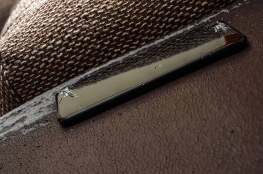 Antika deri bir koltukta kırık bir ekranda akıllı telefon görüntüsü.