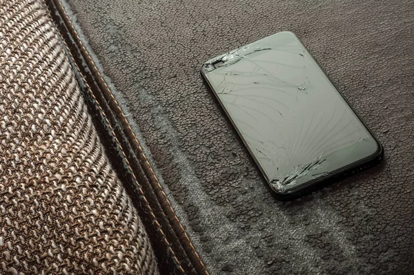 View on a cracked screen of a smartphone on an antique retro leather sofa.