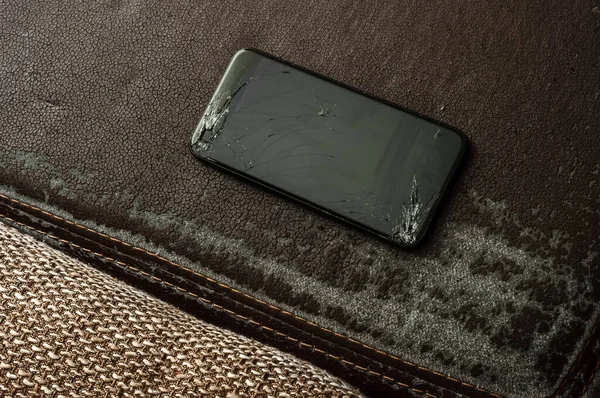 アンティークのレトロな革のソファでスマートフォンの割れた画面で見る — ストック写真