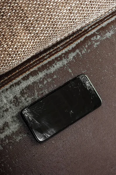 View on a cracked screen of a smartphone on an antique retro leather sofa.