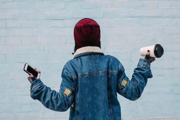 Volta hipster jovem está segurando um café e telefone — Fotografia de Stock