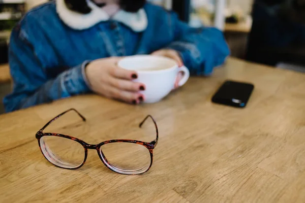 Очки на фоне девушки хипстер кофе в кафе — стоковое фото