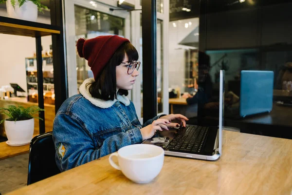 Porträt einer Hipsterin, die in einem Café einen Laptop benutzt — Stockfoto