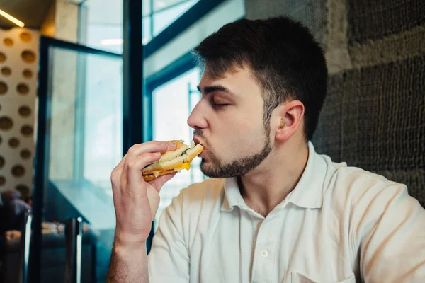 젊은 남자는 레스토랑에서 패스트 푸드를 먹는 즐긴다 — 스톡 사진