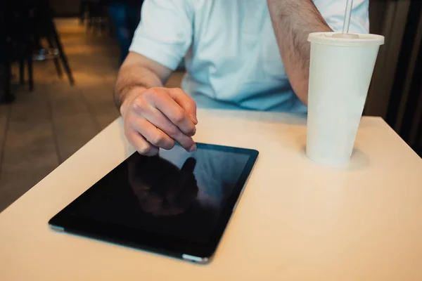 Junger Mann nutzt Tablet-Computer im gemütlichen Restaurant und trinkt Limonade — Stockfoto