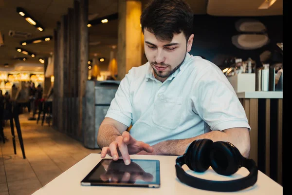 Joven hombre de negocios sentado en un restaurante disfrutando de la tableta y espera su desayuno —  Fotos de Stock
