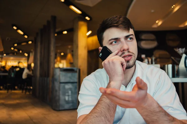 Löst der junge Geschäftsmann am Telefon in einem gemütlichen Restaurant ernste Angelegenheiten. Diese aktiven Gesten — Stockfoto