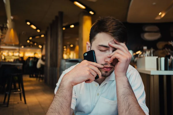 Расстроенный молодой бизнесмен разговаривает по телефону в уютном ресторане — стоковое фото