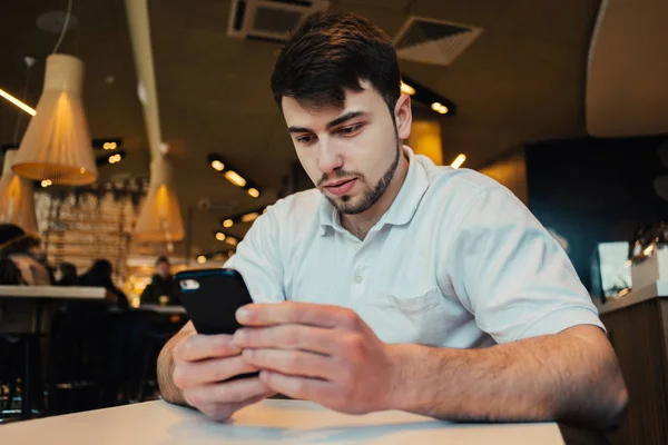 Jungunternehmer benutzt Handy in gemütlichem Café — Stockfoto